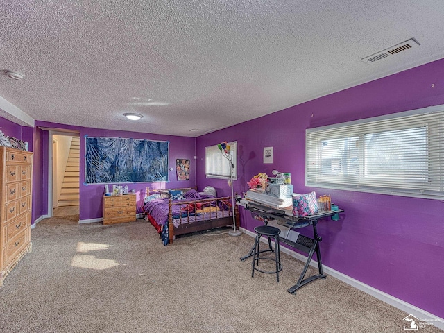 bedroom with multiple windows, carpet floors, and a textured ceiling