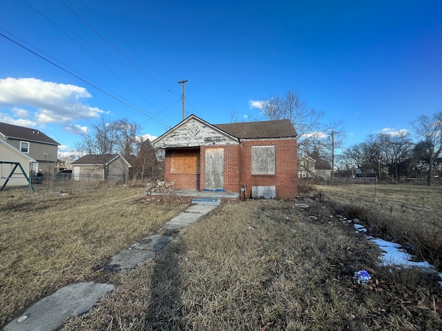 view of front of home with brick siding, a front yard, and fence