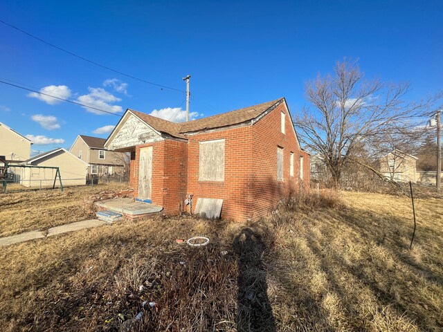 view of property exterior featuring fence and brick siding