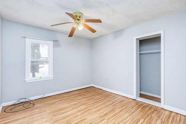 unfurnished bedroom featuring light hardwood / wood-style flooring, a textured ceiling, ceiling fan, and a closet