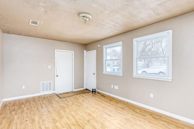 unfurnished room featuring a textured ceiling and light wood-type flooring