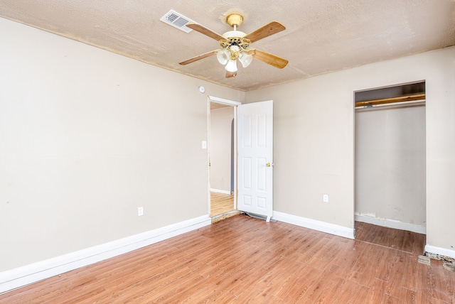 unfurnished bedroom featuring a textured ceiling, wood-type flooring, a closet, and ceiling fan