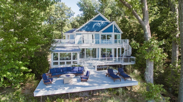 back of property featuring a wooden deck, stairway, an outdoor living space with a fire pit, and a balcony