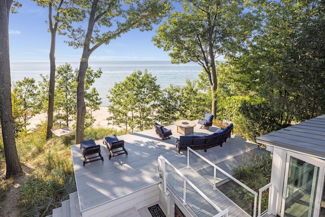 deck with an outdoor living space with a fire pit and a water view