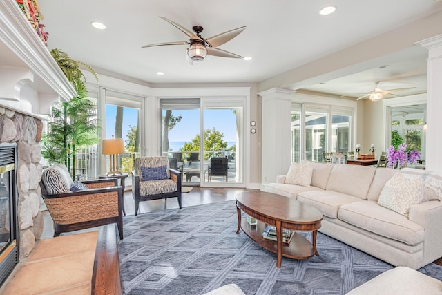 living room featuring a ceiling fan, wood finished floors, ornate columns, a fireplace, and recessed lighting