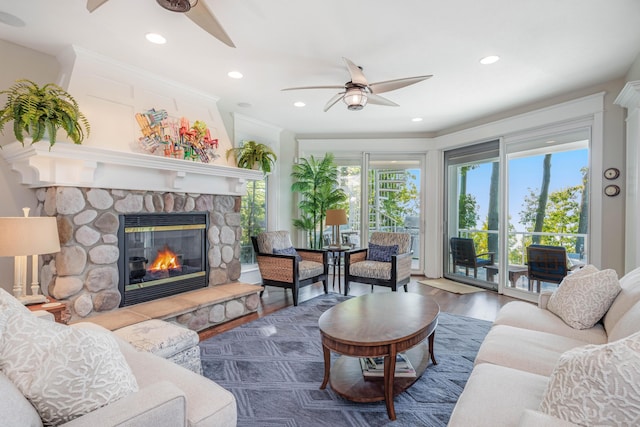 living area featuring crown molding, a fireplace, recessed lighting, ceiling fan, and wood finished floors