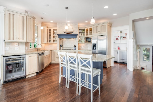 kitchen featuring wine cooler, hanging light fixtures, glass insert cabinets, appliances with stainless steel finishes, and a kitchen island