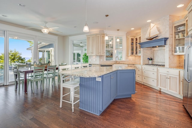kitchen with a kitchen island, glass insert cabinets, light stone countertops, premium range hood, and pendant lighting