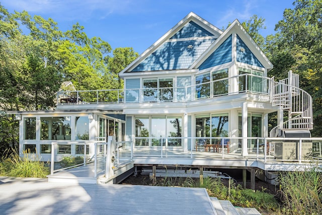 rear view of house featuring a sunroom, stairway, and a wooden deck