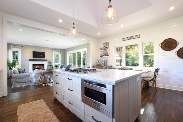 kitchen featuring a center island, dark wood-type flooring, hanging light fixtures, white cabinetry, and stainless steel gas cooktop