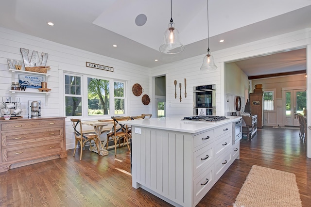 kitchen with dark hardwood / wood-style flooring, plenty of natural light, white cabinets, and pendant lighting