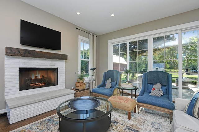 living room with wood-type flooring and a brick fireplace