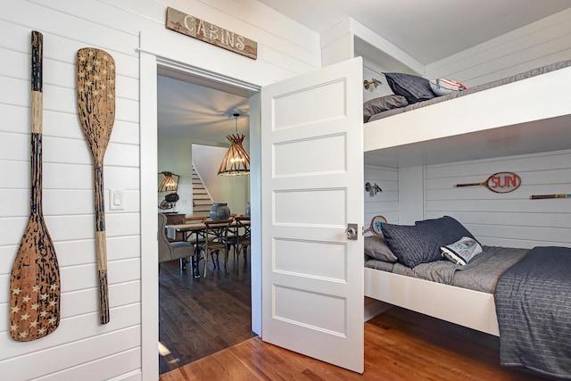 bedroom featuring hardwood / wood-style flooring and wood walls