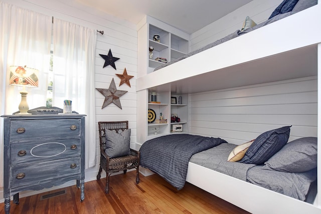 bedroom with wood walls and wood-type flooring