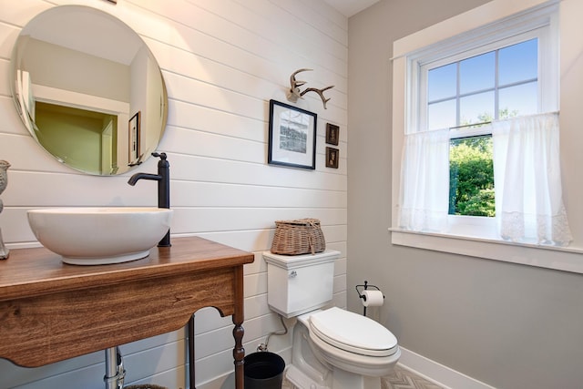 bathroom with wood walls, sink, and toilet