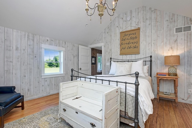 bedroom with a chandelier, light hardwood / wood-style floors, and lofted ceiling