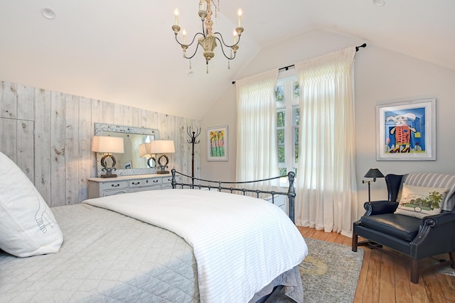 bedroom featuring light wood-type flooring, vaulted ceiling, a notable chandelier, and wood walls