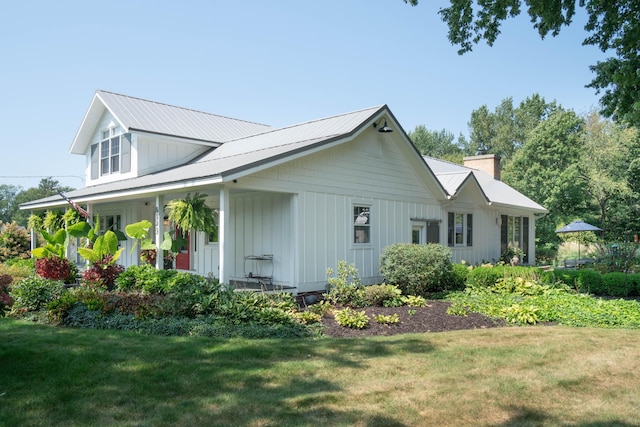 view of side of property with covered porch and a lawn