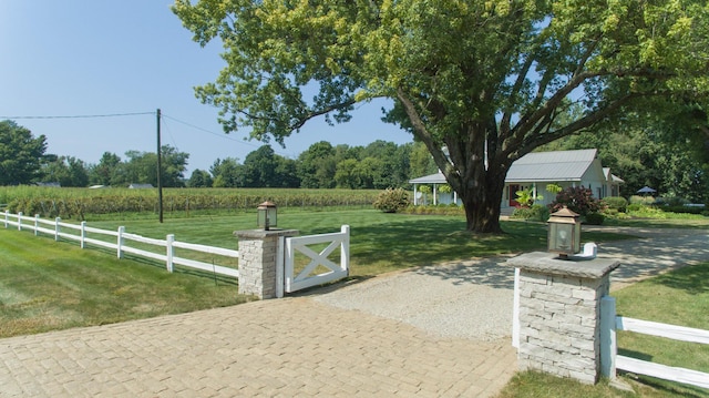 view of gate with a lawn and a rural view