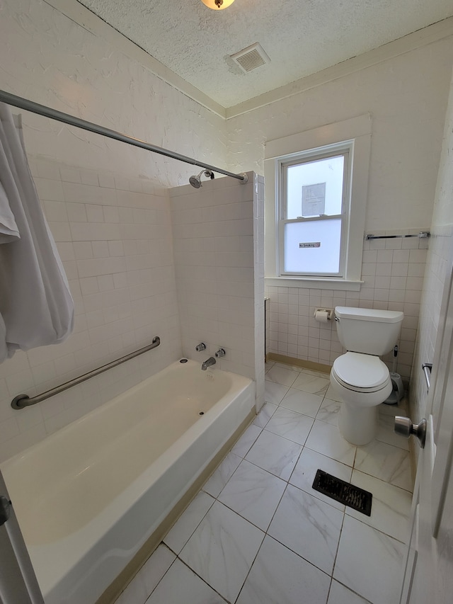 bathroom featuring toilet, a textured ceiling, tile walls, and shower / bath combo