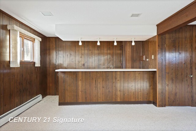 bar with carpet flooring, rail lighting, a baseboard radiator, and wooden walls