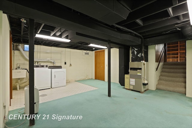 basement featuring carpet, heating unit, sink, and washing machine and clothes dryer