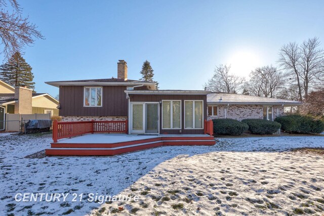 snow covered property with a deck and a sunroom