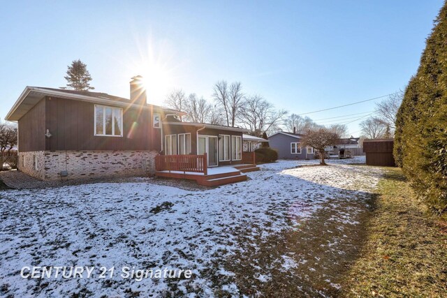 snow covered rear of property featuring a deck