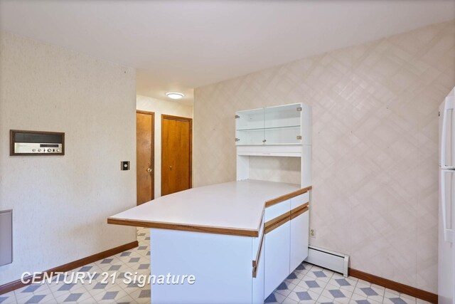 kitchen featuring kitchen peninsula, white cabinets, and a baseboard heating unit