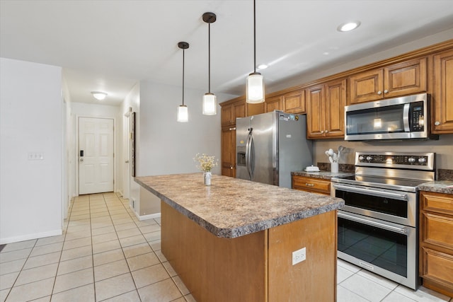 kitchen with appliances with stainless steel finishes, a center island, brown cabinets, and light tile patterned flooring