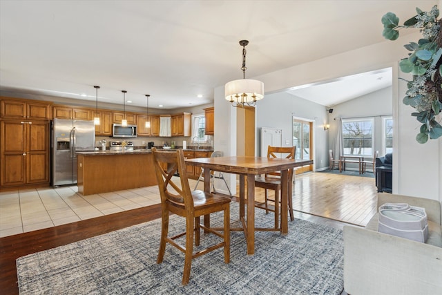 dining room featuring lofted ceiling, light wood finished floors, a notable chandelier, and recessed lighting