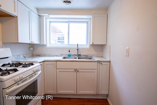 kitchen with sink, white cabinetry, backsplash, and white range with gas cooktop