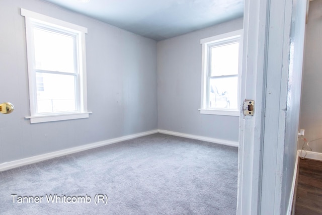 unfurnished room with plenty of natural light and dark colored carpet