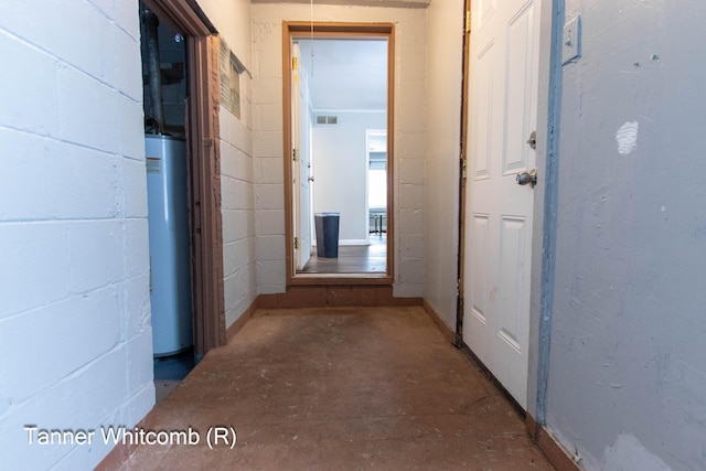 hallway featuring water heater and concrete flooring