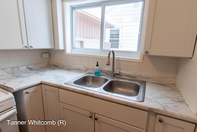 kitchen with sink, white cabinetry, tasteful backsplash, and light stone counters