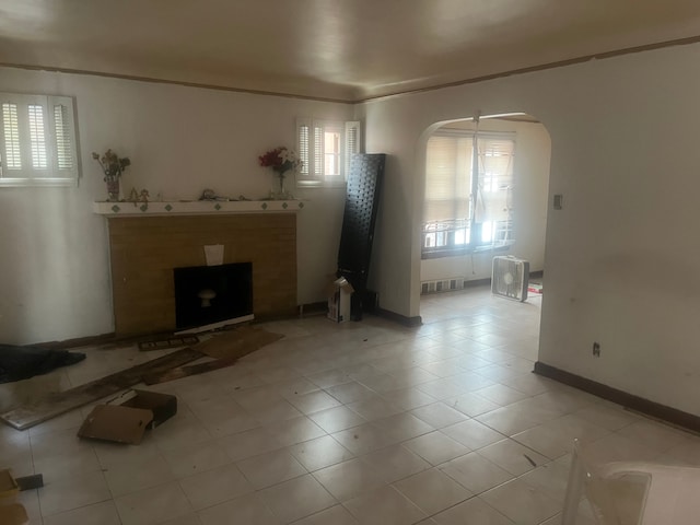 unfurnished living room featuring crown molding and light tile patterned flooring