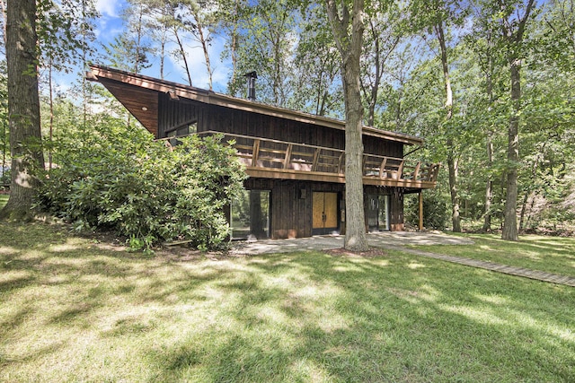 rear view of house featuring a patio, a deck, and a lawn