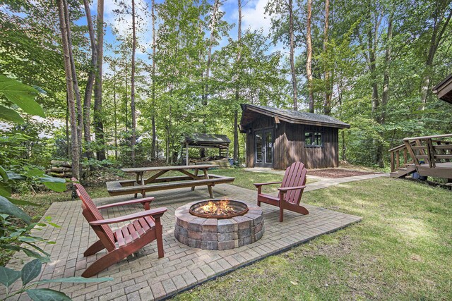 view of yard featuring an outdoor structure, a patio area, and a fire pit