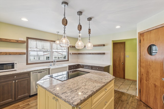 kitchen with light stone countertops, black electric stovetop, stainless steel dishwasher, decorative light fixtures, and a center island