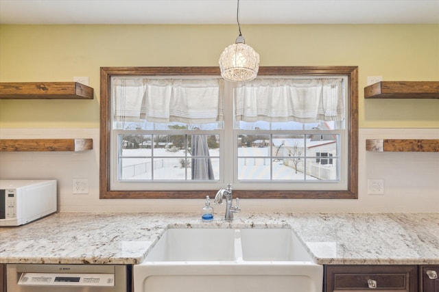 kitchen featuring light stone countertops, sink, pendant lighting, and stainless steel dishwasher