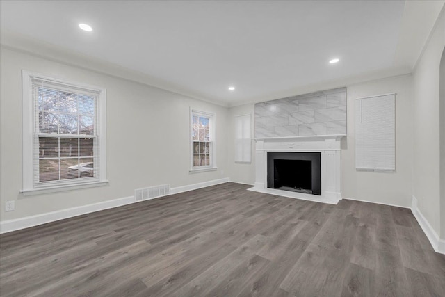 unfurnished living room with hardwood / wood-style flooring, crown molding, and a fireplace