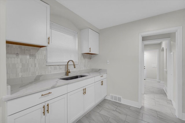 kitchen featuring white cabinetry, light stone countertops, and sink