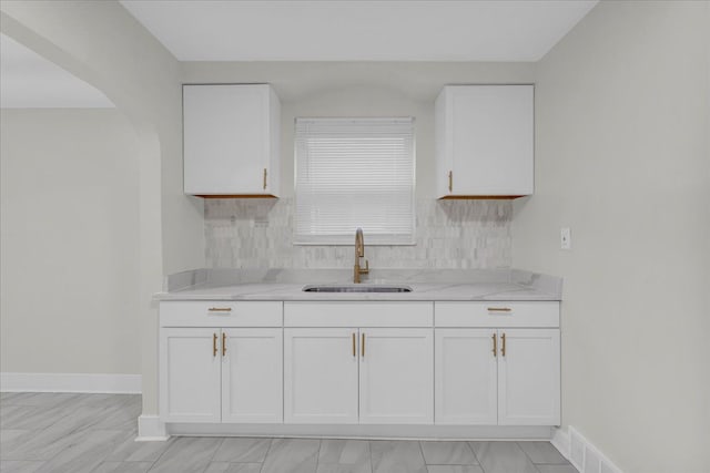 kitchen with white cabinetry, sink, and light stone counters