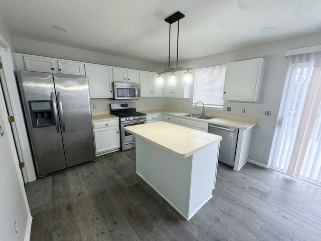 kitchen featuring appliances with stainless steel finishes, sink, a center island, white cabinetry, and hanging light fixtures