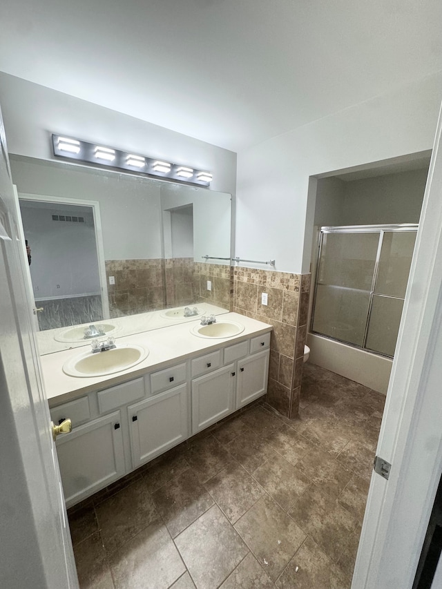 full bathroom with vanity, toilet, tile walls, and enclosed tub / shower combo