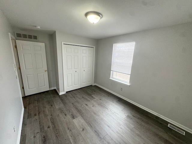 unfurnished bedroom with a closet and dark wood-type flooring