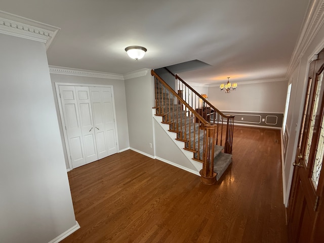 foyer featuring dark wood-type flooring, crown molding, and a chandelier