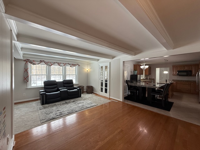 living room with beam ceiling, light hardwood / wood-style floors, crown molding, and a chandelier