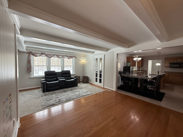 living room with beam ceiling, crown molding, light hardwood / wood-style flooring, and a chandelier