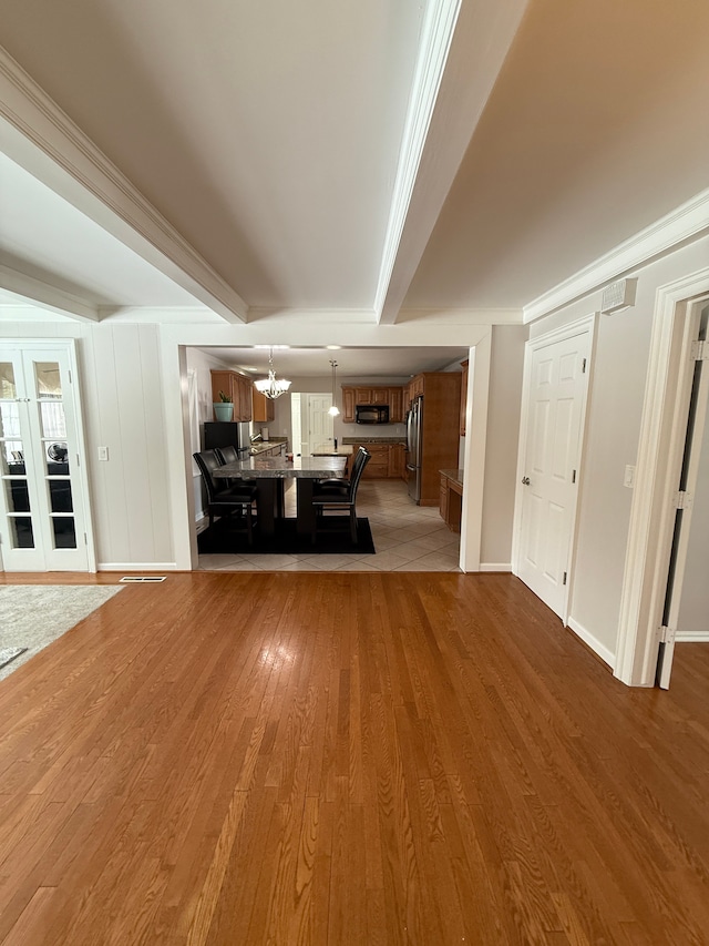 unfurnished living room with wood-type flooring, crown molding, and a notable chandelier